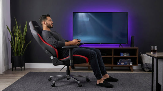 Gamer reclined in a black-and-red ergonomic gaming chair in front of a TV — recline angle for console gaming comfort